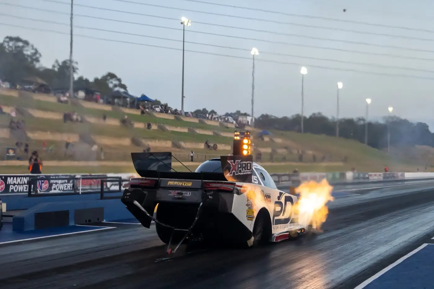 A drag car launching off the line, shot side-on with the exhaust flaring