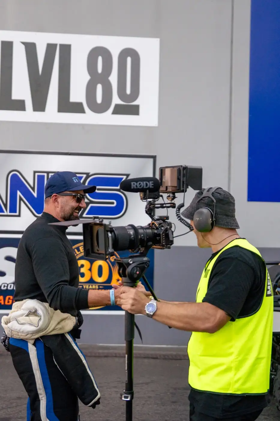 A camera operator filming an interview on location at a motorsport event